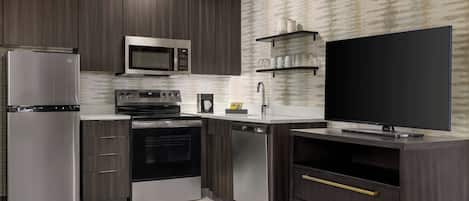 A modern kitchen with stainless steel appliances, dark wood cabinets, and a flat-screen TV.
