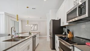 Una cucina moderna con elettrodomestici in acciaio inossidabile, mobili bianchi e luci a sospensione.