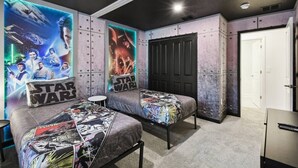 Camera da letto a tema Star Wars con due letti, poster e un armadio.