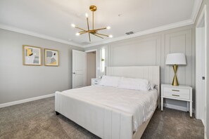 A bedroom with a large bed, bedside tables, a lamp, and a ceiling light fixture.
