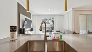Una cucina moderna con un lavello doppio, piani in acciaio inossidabile e illuminazione a sospensione.
