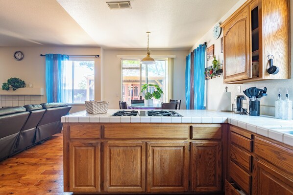 Una cocina con armarios de madera, una isla central, una estufa y un comedor con mesa y sillas.