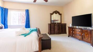 A bedroom with a bed, a dresser, a television, and a ceiling fan.