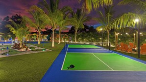 An outdoor tennis court with surrounding palm trees and seating areas. - Private Splash Pad, Pickleball, Htd. Pool, Hot Tub (Bradenton)
