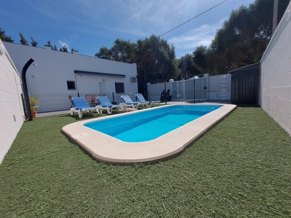 A swimming pool with artificial grass, a white building, and a fence. - Country House 'Alex 2' with Private Pool, Wi-Fi and Air Conditioning (Zahora)