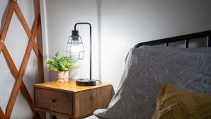Un letto con un cuscino decorato, un comodino con una lampada e una pianta.
