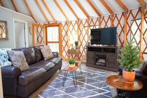 Una sala de estar acogedora con un sofá de cuero, un televisor de pantalla plana, una chimenea y un revestimiento de pared de madera.