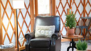 A leather armchair with a fluffy pillow, a small round table with a potted plant, and a wooden lattice wall.