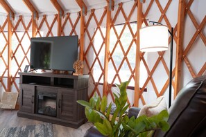 A living room with a TV, wooden lattice walls, a fireplace, and a lamp.