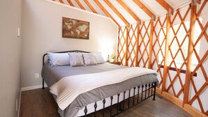 Une chambre avec un lit, une cloison en treillis de bois et une carte accrochée au mur.