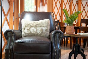 Un fauteuil en cuir avec un coussin moelleux, une plante en pot et une table à manger avec des chaises, le tout dans une pièce dont les murs sont recouverts de treillis en bois.