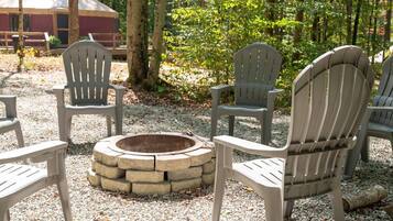 Outdoor seating with Adirondack chairs around a stone fire pit.