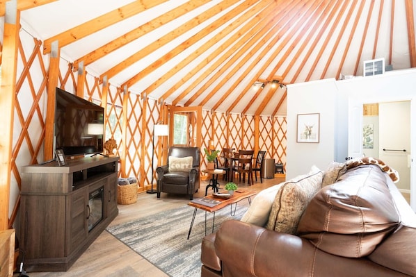 Un intérieur chaleureux avec un plafond en bois, un canapé en cuir, un téléviseur et un coin repas.