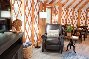 A cozy room with a leather armchair, a wooden table with a plant, and a TV on a wooden stand.