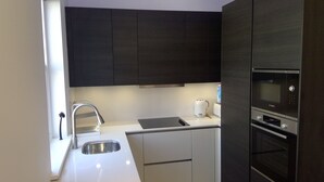 A modern kitchen with dark cabinets, a stainless steel sink, a Bosch microwave, and a coffee maker.