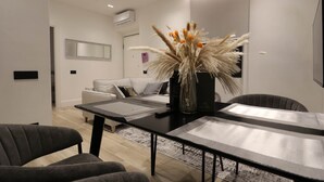 Un salon moderne comprenant un coin repas, un ensemble de canapés et un vase décoratif contenant des plantes séchées.