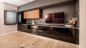 A modern kitchen with a built-in oven, wooden cabinets, and a large flat-screen TV. - Suite Monte Nero · Renovated 1BR in Central Olbia with King Bed · Modern Style (Olbia)