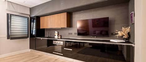 A modern kitchen with a built-in oven, wooden cabinets, and a large flat-screen TV.