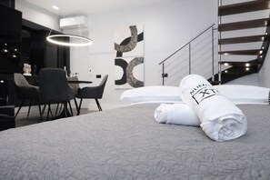 Ein modernes Hotelzimmer mit einem ordentlich bezogenen Bett, einer Essecke mit Stühlen und einer Treppe.
