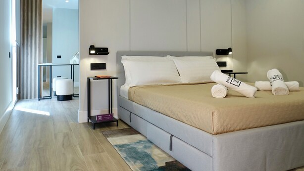 A modern bedroom with a large bed, bedside tables, and a desk.