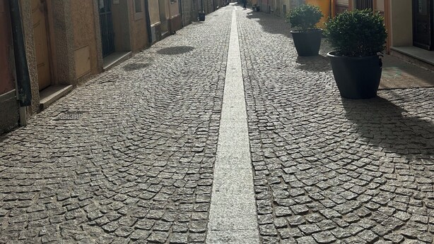 Una calle adoquinada flanqueada por edificios históricos, con balcones y arquitectura tradicional.