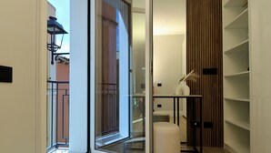 Un interior moderno con un vidrio que da a un espacio exterior, un panel de pared de madera y una pequeña mesa con un florero.