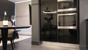Una cocina moderna con microondas y horno integrados, un comedor con mesa y sillas, y una lámpara colgante grande.