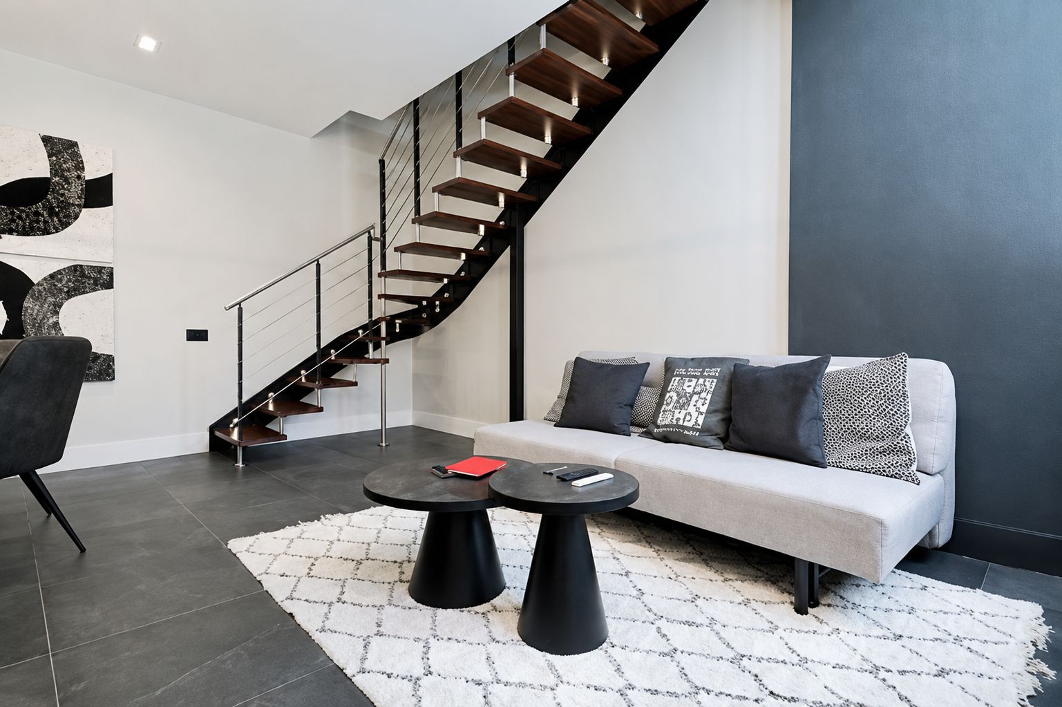 A modern living room with a staircase, a sofa, and a coffee table.
