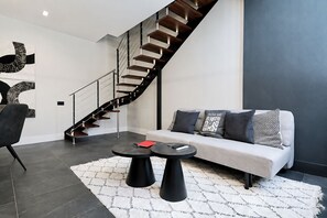 Un salon moderne avec un escalier, un canapé et une table basse.