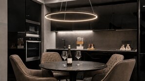 A modern kitchen with a round dining table, four chairs, and a pendant light. - Cavour Suites 31, Olbia Old Town Duplex, King Bed, Office, Gated Parking (Olbia)