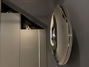 A modern, minimalist room with a built-in, circular, metallic object on the wall, possibly a decorative piece or appliance. - Garibaldi Suites 4 · Renovated 1BR Ground-Floor Suite in Olbia Historic Centre (Olbia)