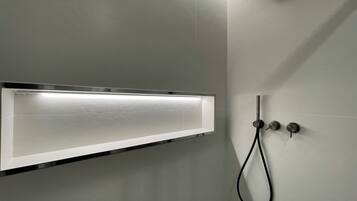 A modern shower enclosure with a wall-mounted control panel and a handheld showerhead.