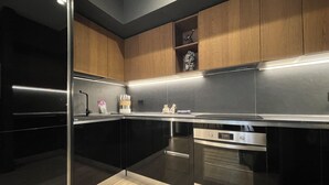 Cozinha moderna com eletrodomésticos pretos, armários de madeira e bancada de aço inoxidável.