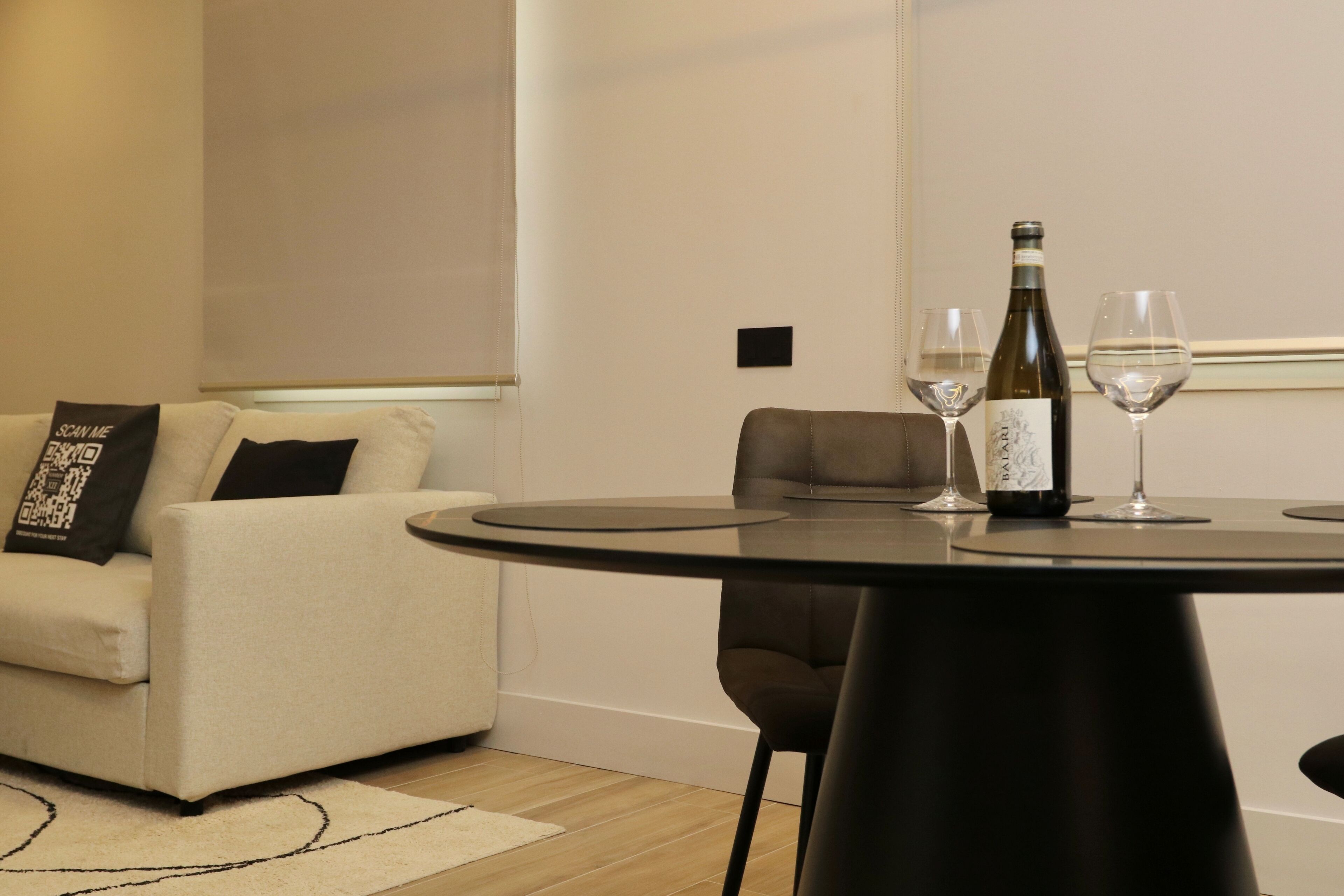 Een moderne woonkamer met een ronde tafel, een bank en een fles wijn.