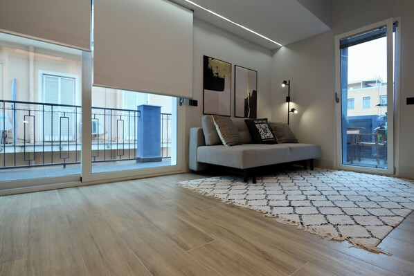 A modern living room with a sofa, a patterned rug, and artwork on the wall.