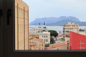 A coastal cityscape with buildings, a marina, and mountains in the background.