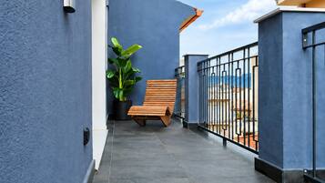 A balcony with a wooden bench, a potted plant, and a view of the sea.
