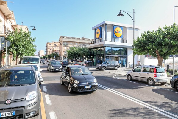 Una calle urbana concurrida con coches, un supermercado Lidl y edificios residenciales.