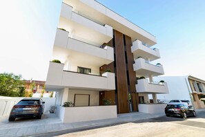 Ein modernes, mehrgeschossiges Wohngebäude mit Balkonen, einer Garage und einer Auffahrt.