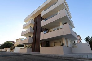 Un immeuble résidentiel à plusieurs étages, doté de balcons, d’une entrée principale et d’une enseigne indiquant son nom.