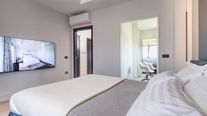 A modern hotel room with a large bed, a flat-screen TV mounted on the wall, and a walk-in closet with a mirror. - AZULIS Apartment 7 · 2BR with Terraces & Elevator in Aldo Moro (Olbia)