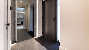 Ein moderner Flur mit einer dunklen Holztür, einer strukturierten Wand und Blick in einen Küchenbereich.