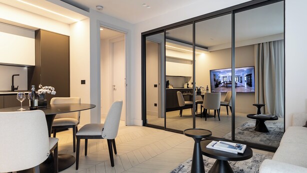 Une chambre d’hôtel moderne comprenant un coin repas, un espace de vie avec un canapé et une table basse, ainsi qu’un téléviseur dans l’espace de vie.