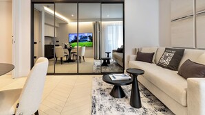 Un salon moderne avec un canapé, une table basse et un téléviseur en arrière-plan.