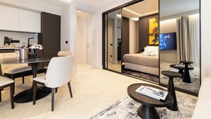 Une chambre d’hôtel moderne dotée d’un coin repas, d’un canapé, d’une télévision et d’un grand miroir.