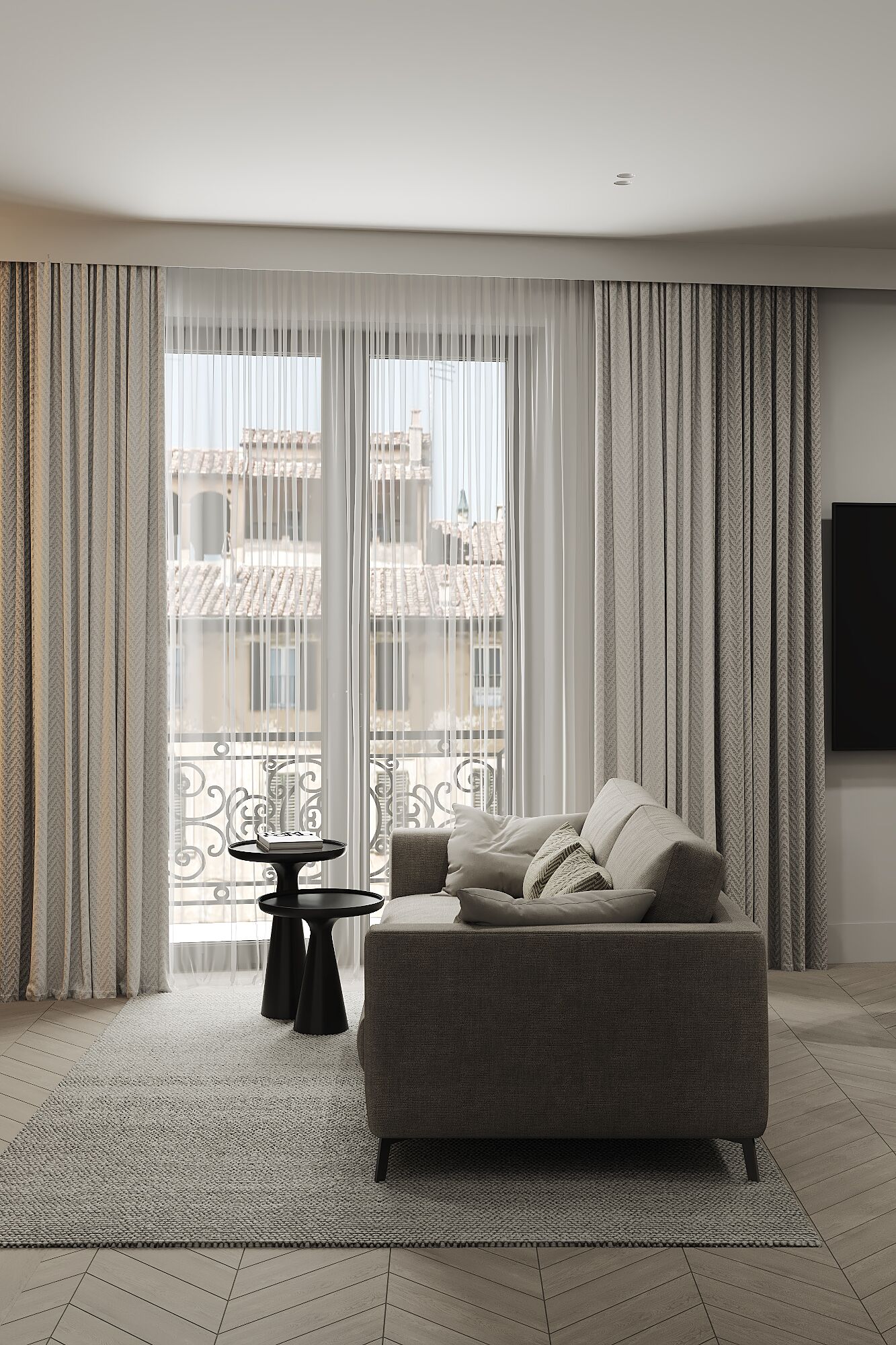 A modern living room with a grey sofa, a small black side table, and a large window with sheer curtains.