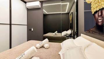 A modern hotel room with a bed, a mirror, and an air conditioning unit.