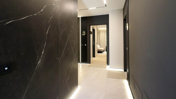A modern hallway with a marble wall, a door labeled '5', and a well-lit interior.