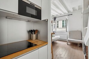 A modern kitchen with a built-in oven, a wooden countertop, and a window overlooking a balcony. - ID 1081 Montorgueil / Rue Tiquetonne (Paris)