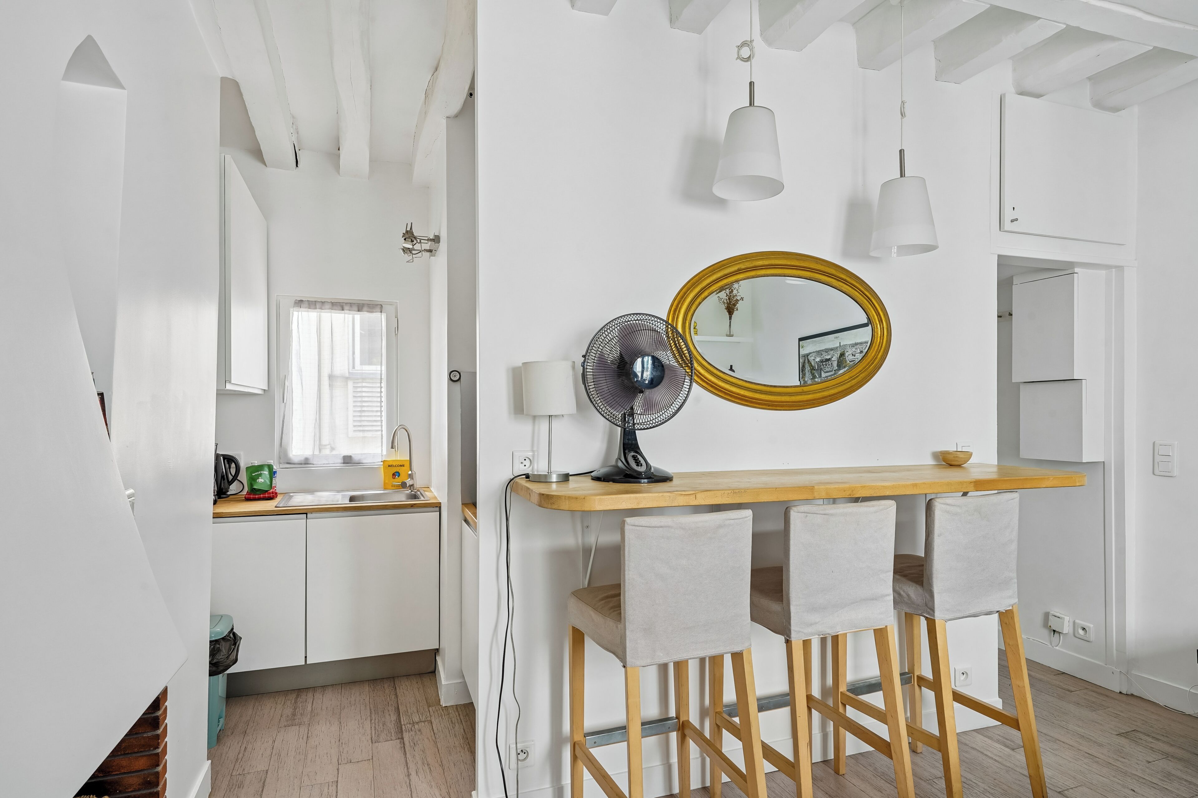 Eine moderne Küche mit weißen Schränken, einem Holztisch und einem Spiegel mit goldener Rahmung.